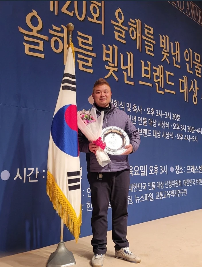 2024 올해를 빛낸 인물 대상 행사장에서 상패와 꽃을 든 김기철 대표
